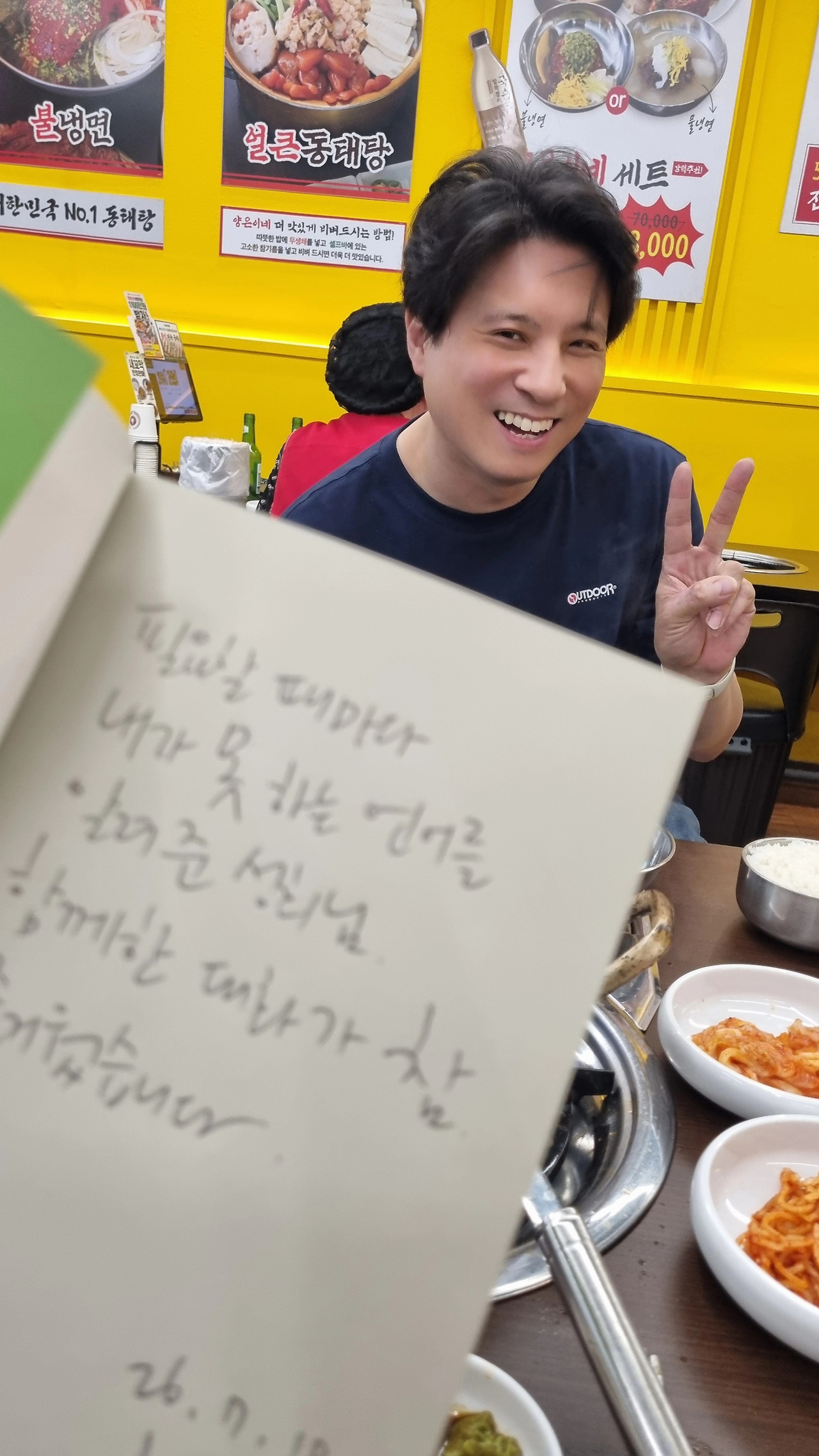 냉면집에서 손편지를 들어 보이며 브이 하는 저자
